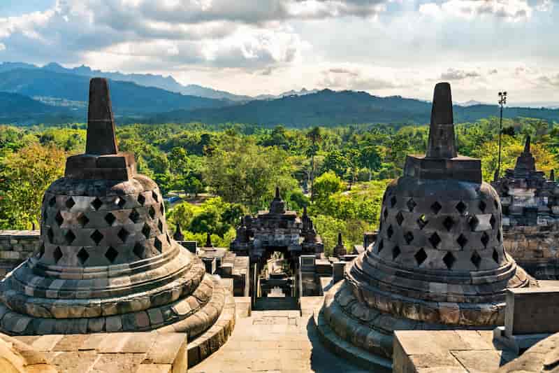 Borobudur Temple with ancient stone stupas and lush green landscape in Java, Indonesia.