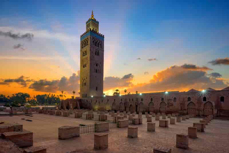 Koutoubia Mosque in Marrakech, Morocco, at sunset with golden light and dramatic clouds.