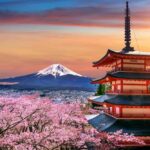 Sunset view of Mount Fuji behind Chureito Pagoda surrounded by pink cherry blossoms in Fujiyoshida, Japan.