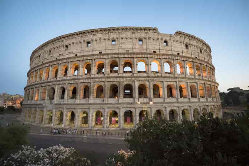 Evening view of the illuminated Colosseum in Rome, Italy against a twilight sky.