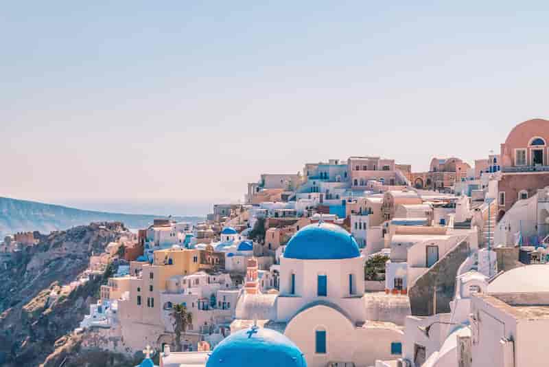 Iconic blue-domed churches and whitewashed houses overlooking the Aegean Sea in Oia, Santorini, Greece.